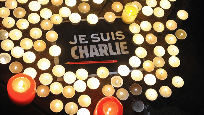 Candles are placed next to a sign reading 'Je suis Charlie' (I am Charlie) and a pen in La Rochelle on January 7, 2015, as people gathered to pay tribute to the twelve people killed in an attack by two armed gunmen on the offices of French satirical newspaper Charlie Hebdo in Paris. (AFP Photo/Xavier Leoty)