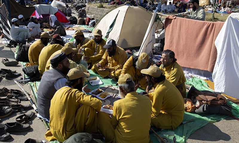 JUI-F supporters have their meal along a roadside during the Azadi March in Islamabad.  AP
