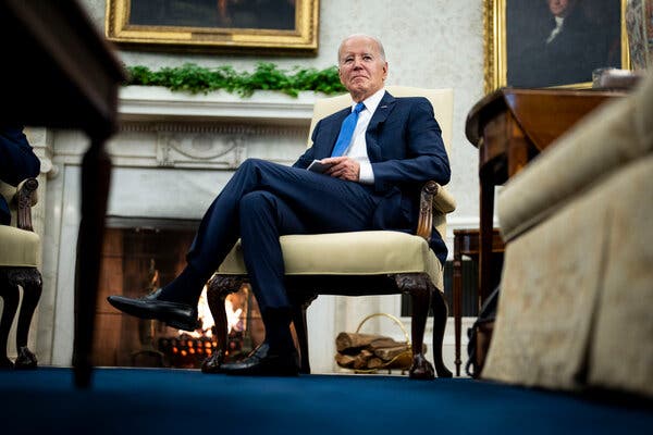 President Biden sitting in a chair in front of a fireplace in the White House.